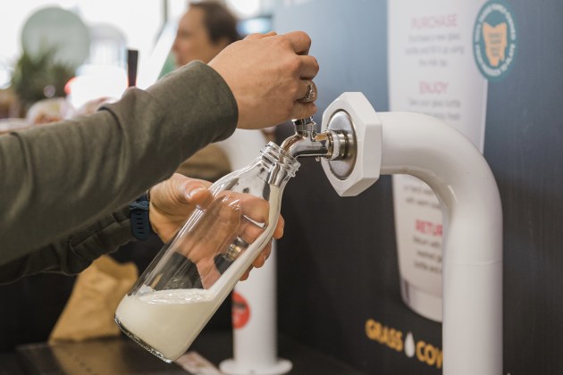 Milk being dispensed from a reusable stainless-steel keg system designed to replace single-use plastic bottles.